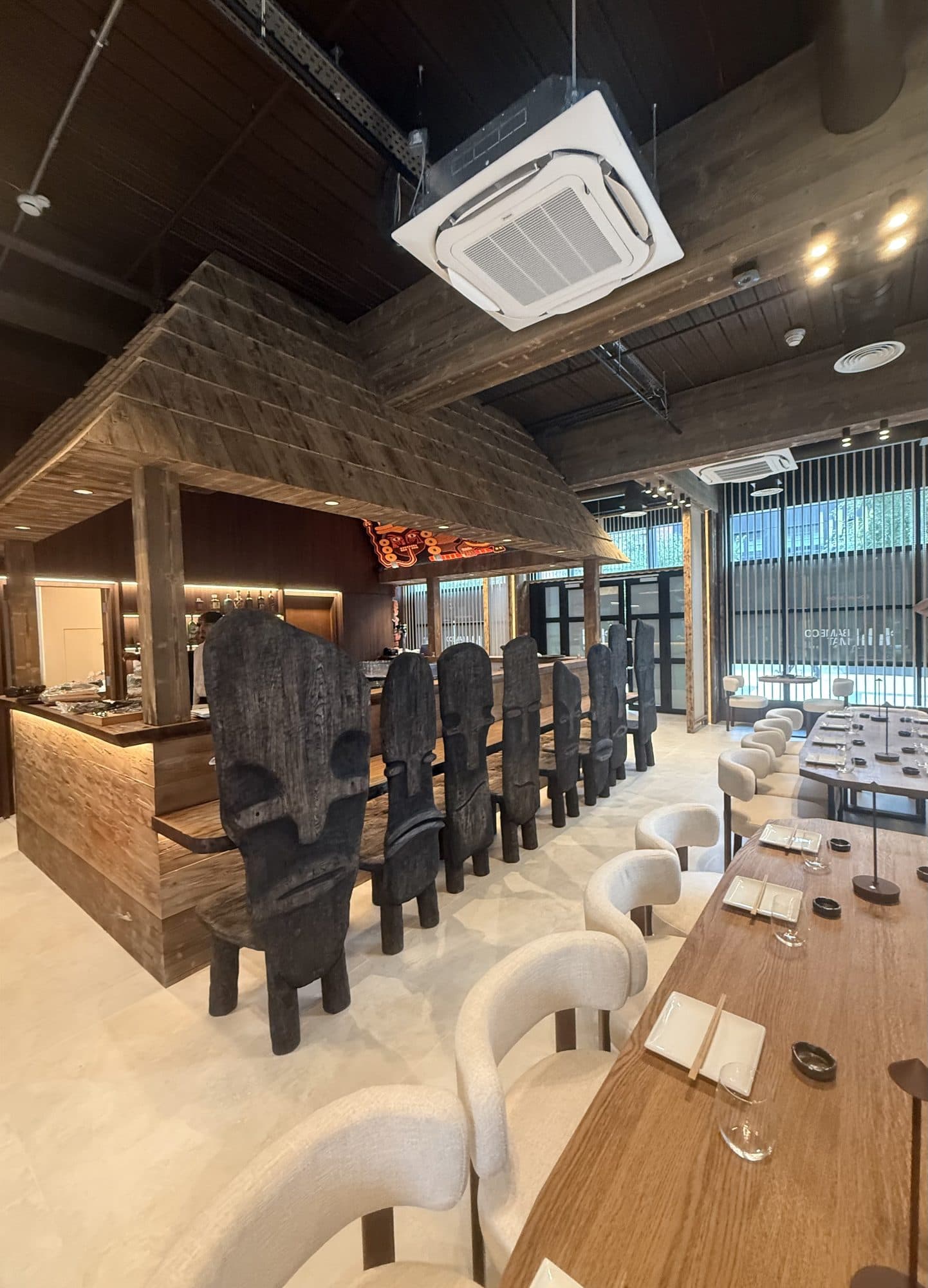 The bar under its timber canopy, with carved chairs and a ceiling cassette above