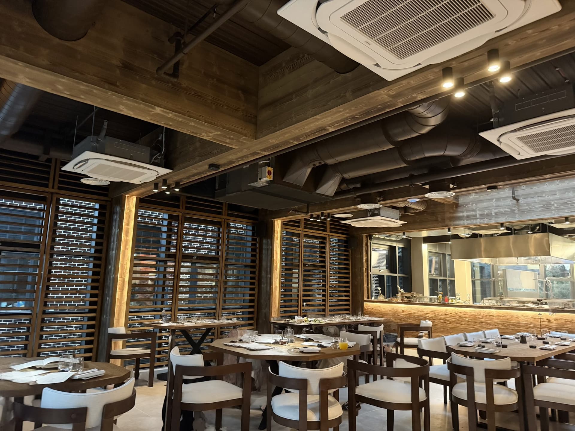 The finished dining room at Bamboo Mat: ceiling cassettes, exposed spiral ductwork and spot lighting set into the timber ceiling, with the open kitchen beyond