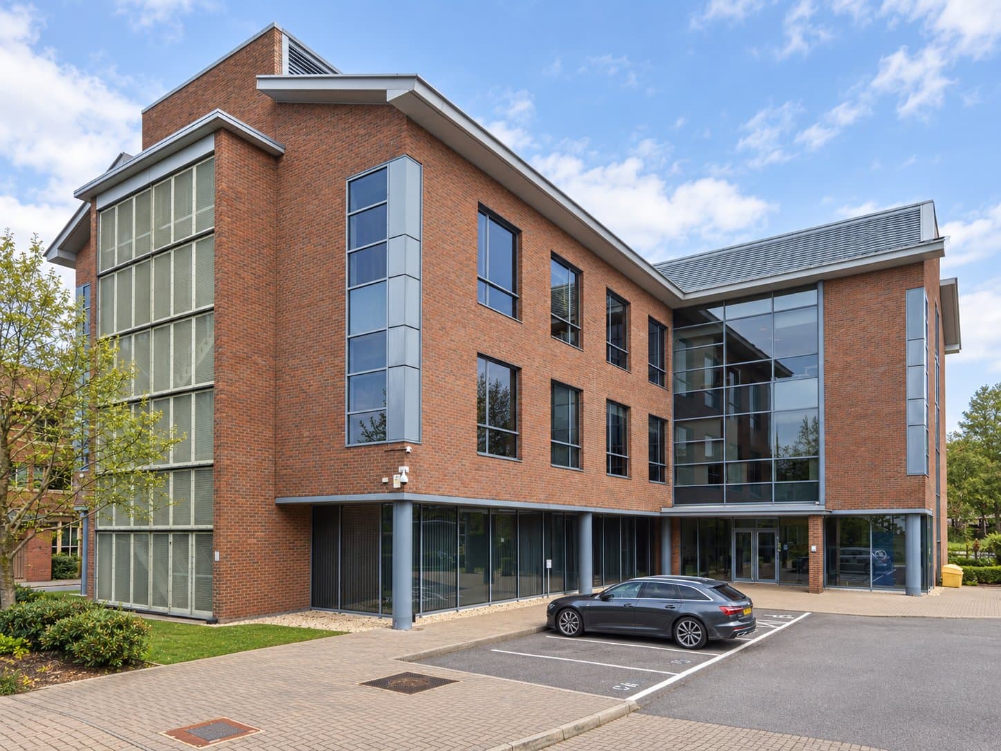 One of the two former office buildings at Waterfront Business Park, Fleet: red brick with a glazed stair tower and full-height entrance glazing